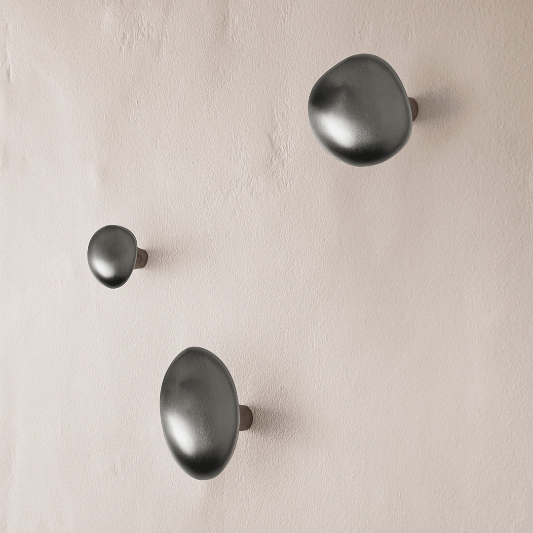 Matte black wall hooks in various sizes against a neutral beige background, showcasing a smooth, modern design.