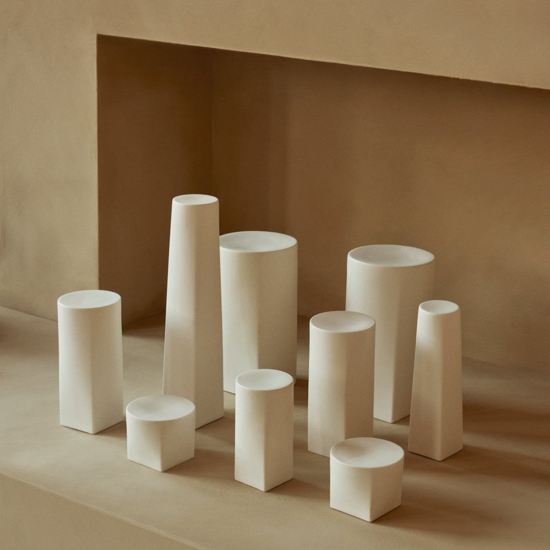 Assorted white vases in various geometric shapes against a neutral beige backdrop. Elegant minimalist design.