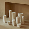 Assorted white vases in various geometric shapes against a neutral beige backdrop. Elegant minimalist design.