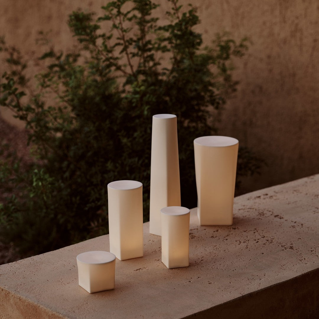 "Set of five minimalist candles in soft beige and white tones, featuring smooth geometric shapes."