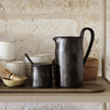"Elegant black ceramic pitcher and sugar bowl with a smooth finish, set against light stoneware background."