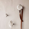 Sleek metallic wall hooks in silver tones with a smooth, rounded design against a neutral background.