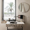 Natural stone sink with soft beige hues and dark circular basin, complemented by minimalist black and white accents.