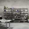 "Modern black shelving unit with a mix of geometric decor, books, and plants against a concrete backdrop."