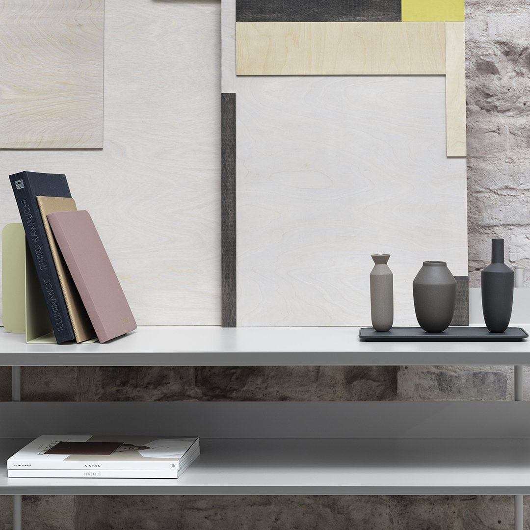 Neutral tones with subtle textures; minimalist decor featuring gray, beige, and muted green patterns on a clean white shelf.