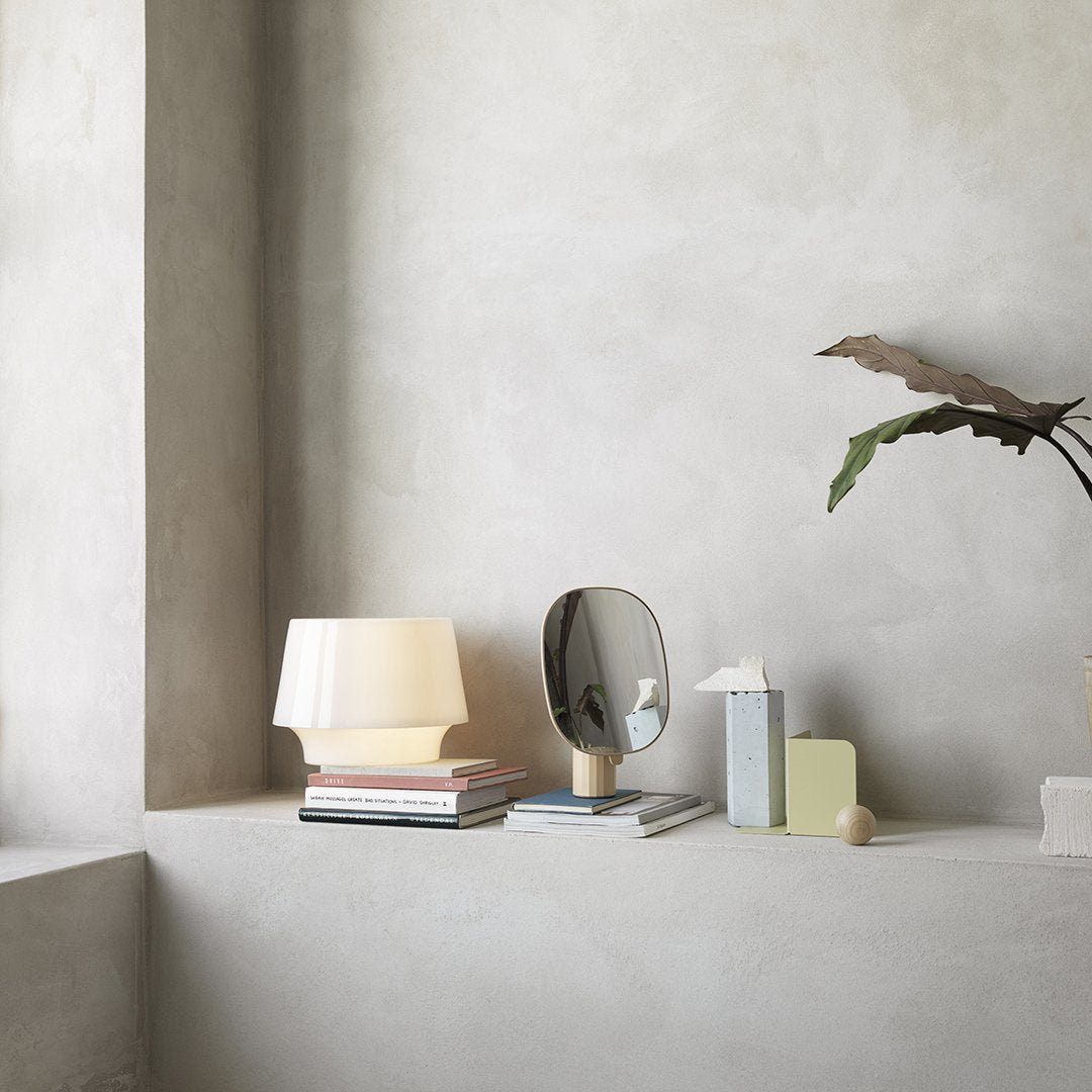 Modern decor featuring a beige lamp, gray books, and light green accents against a textured concrete background.