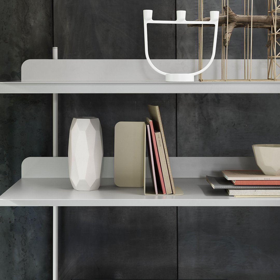 Minimalist white shelving with geometric patterns, gray backdrop, and elegant decor accents in neutral tones.