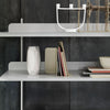 Minimalist white shelving with geometric patterns, gray backdrop, and elegant decor accents in neutral tones.