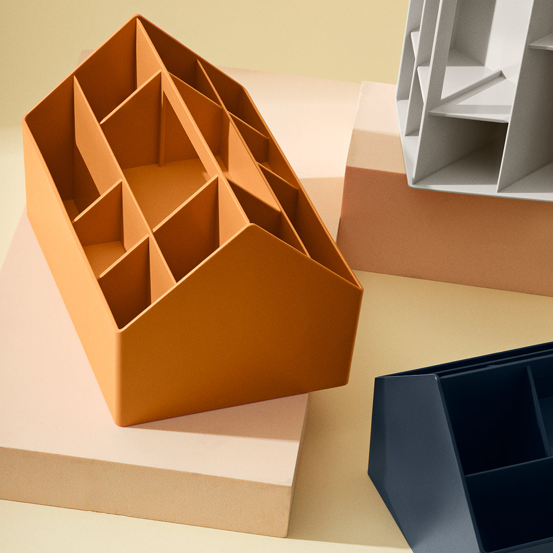 "Stylish organizer in warm orange, sleek navy, and neutral gray on soft pastel backdrop."