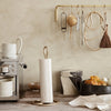 Elegant white paper towel holder with textured pattern against a neutral beige backdrop, featuring gold accents.