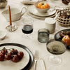 Elegant table setting featuring muted tones, transparent glassware, and rich, earthy colors with textured ceramic accents.