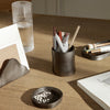 "Dark gray ceramic pen holder and tray with a smooth finish, set on a light wooden desk."