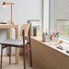 Modern desk scene featuring a light wood finish, a gray seat with reddish-brown accents, and pastel stationery items.