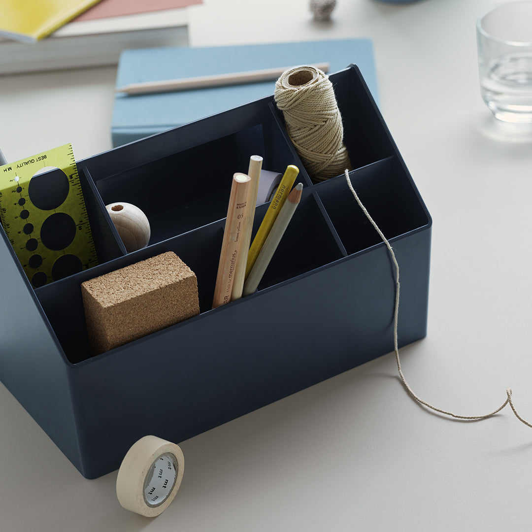 Navy blue organizer with assorted stationery, featuring vibrant patterns in green, white, and natural wood tones.